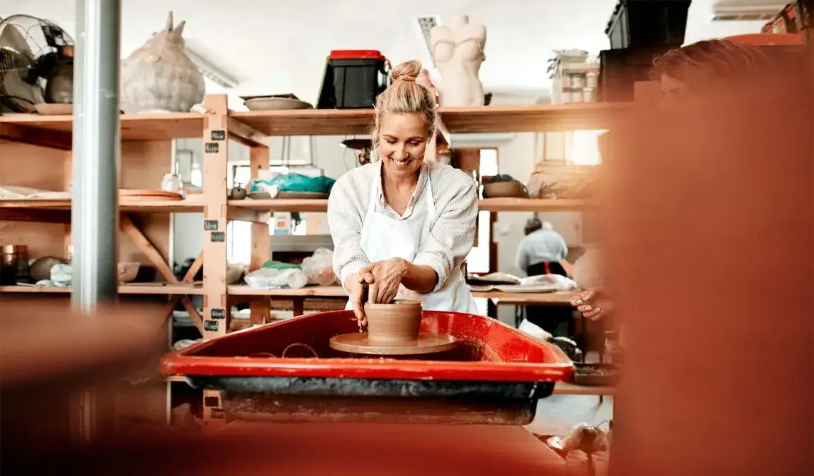 osoba lepiąca z gliny w jasnej pracowni ceramicznej