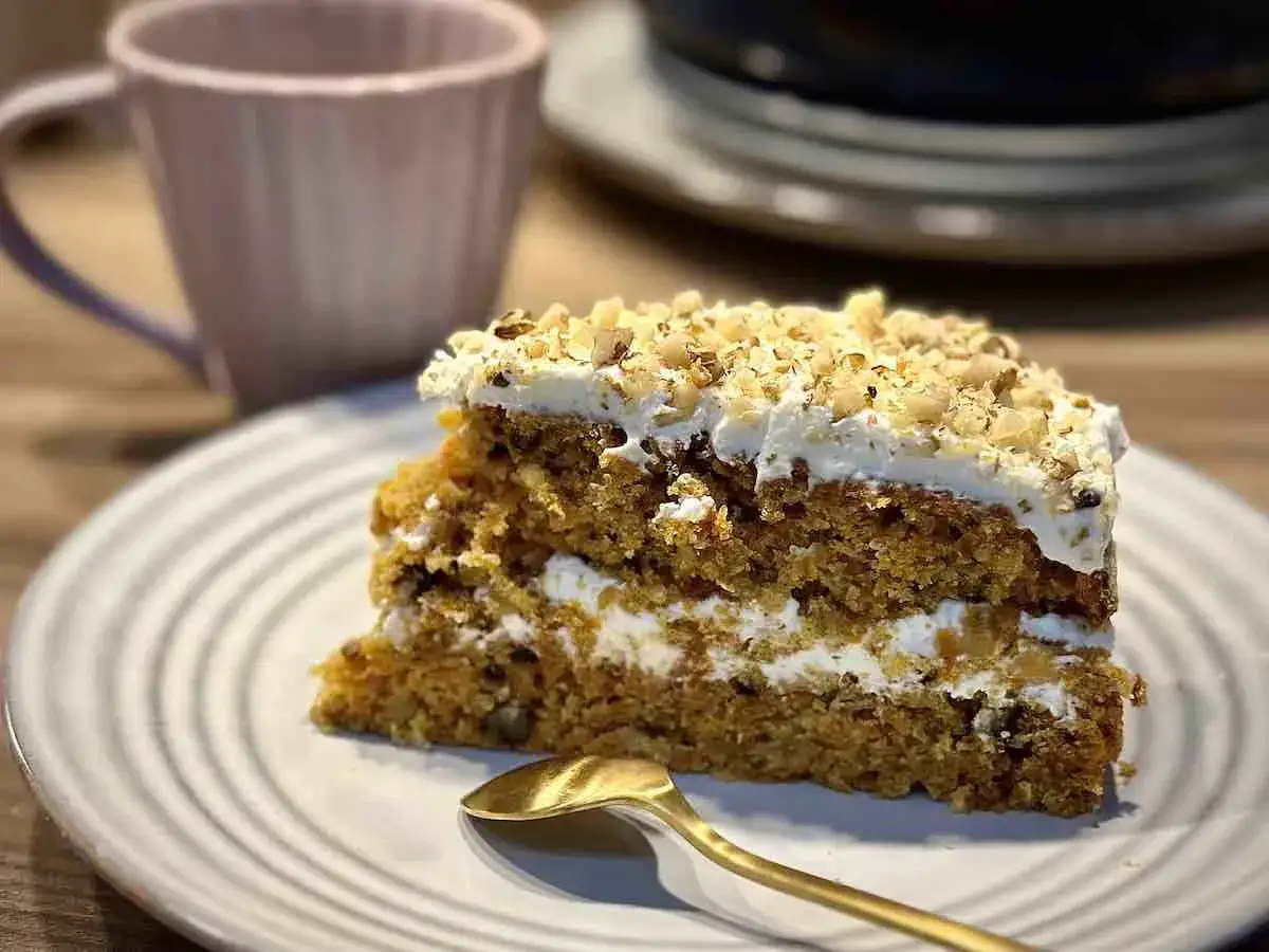 Wilgotne ciasto marchewkowe z kremem mascarpone, posypane orzechami. Idealne na deser z kawą.