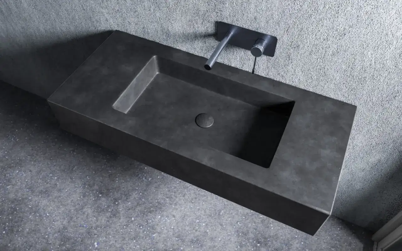 Nowoczesna umywalka z betonu, minimalistyczna, z chromowaną baterią ścienną.