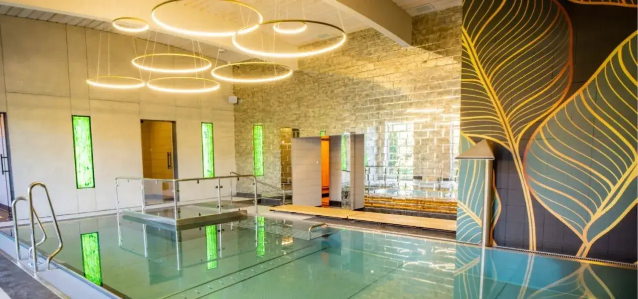 Nowoczesny basen z designerskimi lampami i dekoracjami ściennymi, idealne miejsce na relaks w najlepszym spa w Polsce.