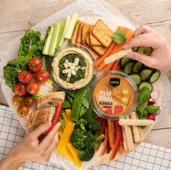 talerz hummusu z warzywami i pieczywem