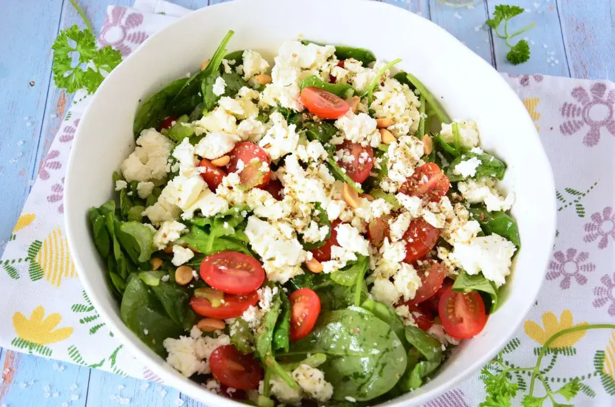Pyszna sałatka ze szpinakiem, pomidorkami koktajlowymi i fetą. Idealna na lekki posiłek.