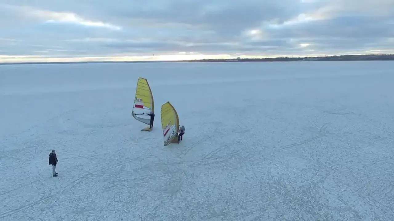 Dwie osoby uprawiają windsurfing na zamarzniętej powierzchni. Czy zatoka Gdańska zamarza? Tak, wygląda na to, że tak.