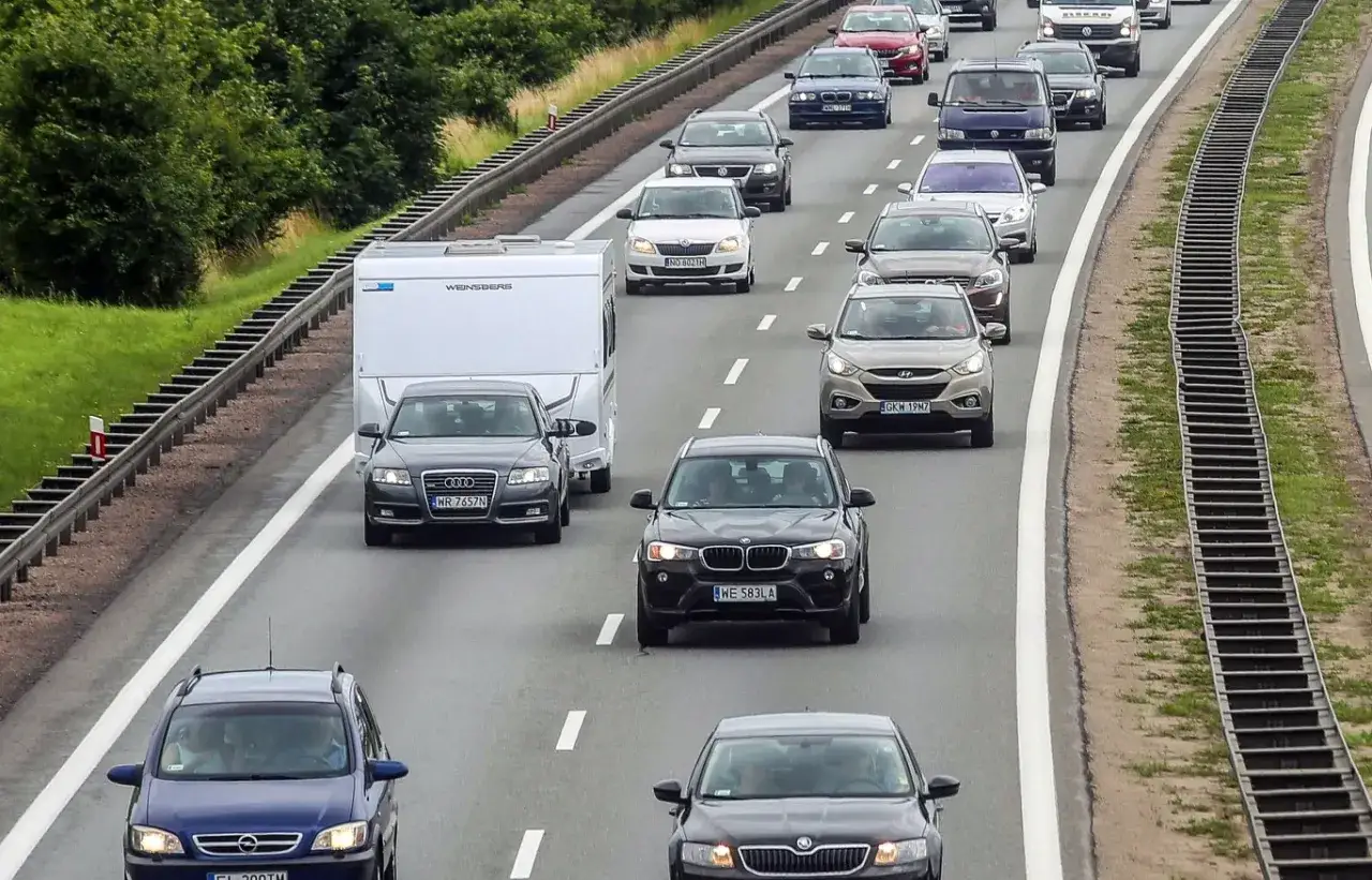 Ruch na autostradzie, samochody i przyczepa kempingowa. Zastanawiasz się, ile można jechać w terenie niezabudowanym?