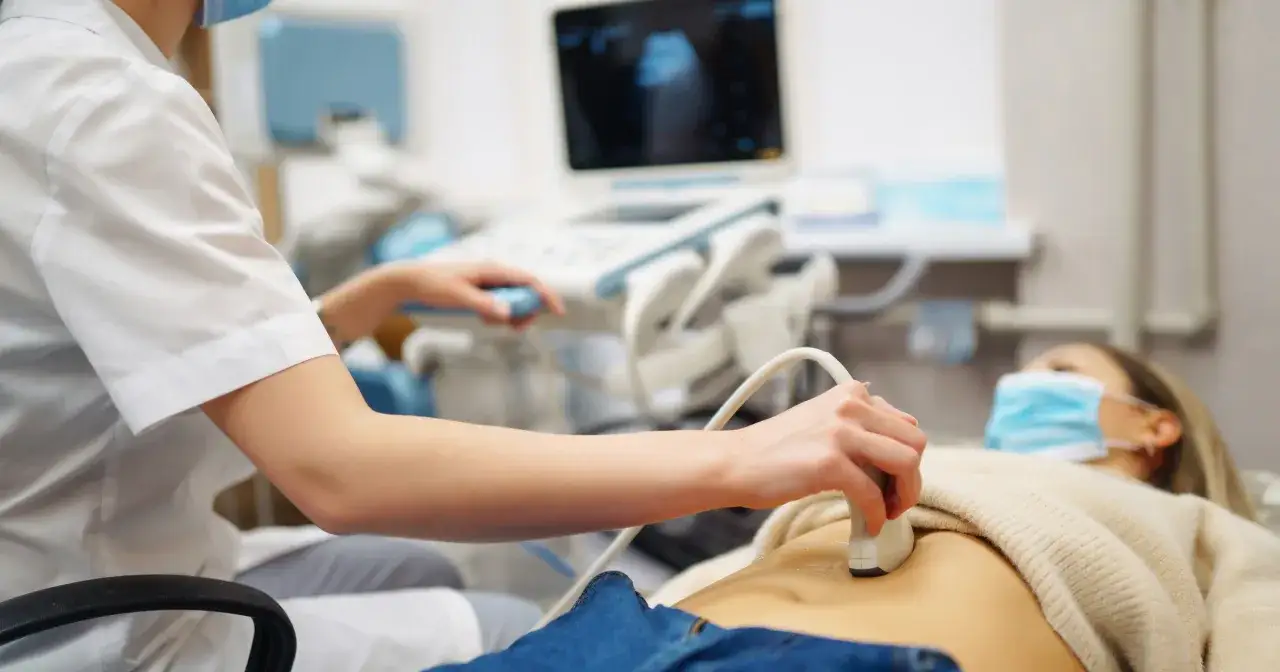 Lekarka wykonuje USG brzucha pacjentki, która stara się o dziecko. Badanie pomaga ocenić, ile trwają starania o dziecko.