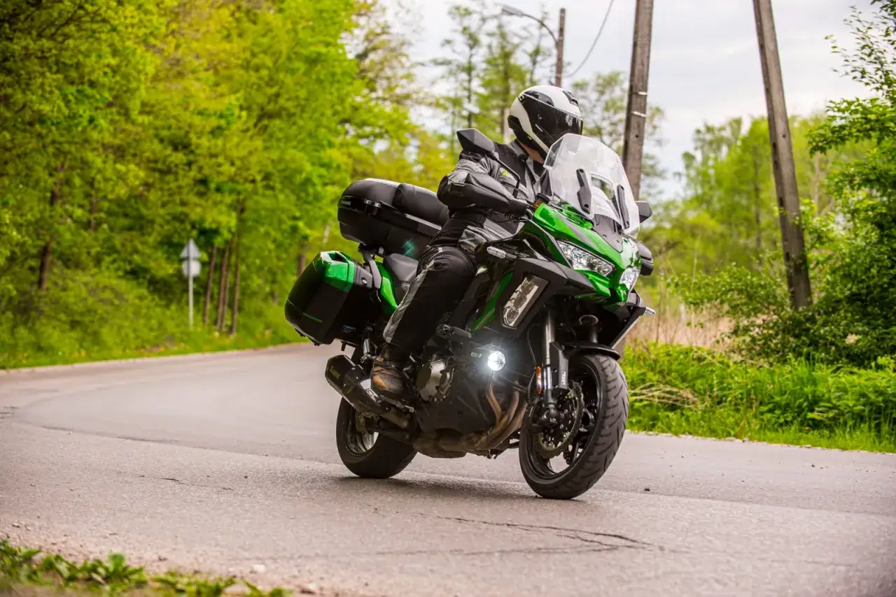 Motocyklista na zielonym Kawasaki Versys 1000, który mimo swoich zalet, ma też pewne wady.