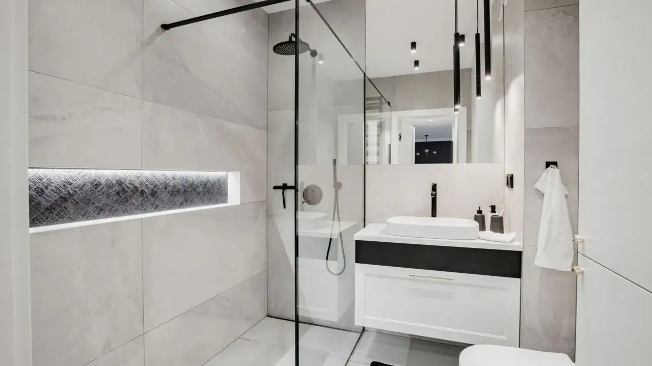 Nowoczesna, bardzo mała łazienka z prysznicem, umywalką i podświetloną wnęką.