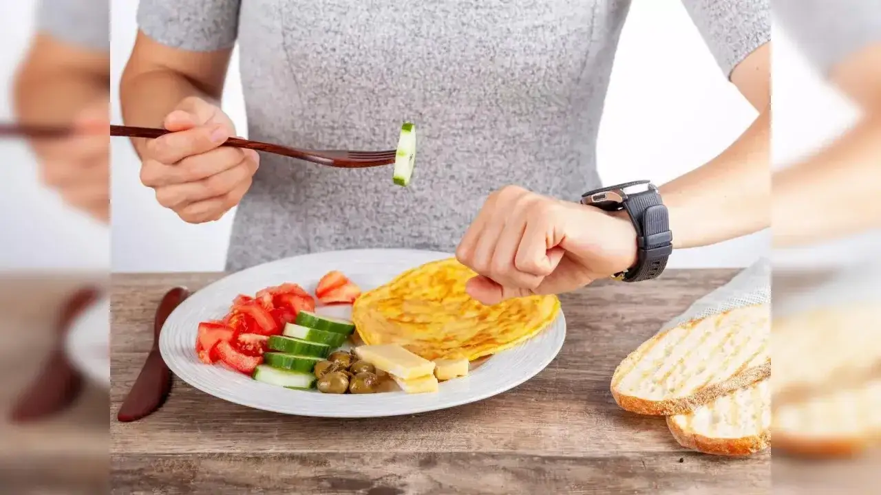 Osoba sprawdza zegarek, jedząc omlet z warzywami i serem. Idealny jadłospis na dieta odchudzająca dla leniwych.