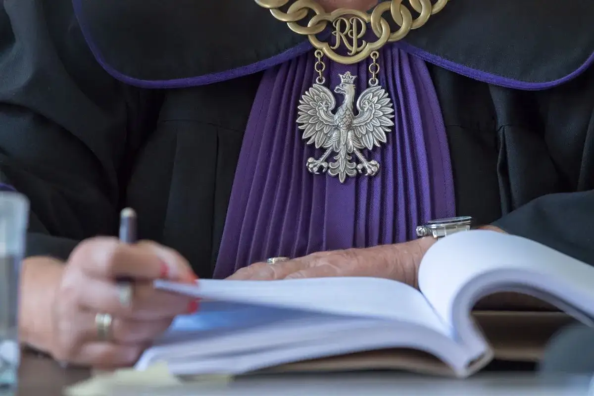 Sędzia w todze z orłem, pochylony nad księgą. Czy sędziowie płacą składkę zdrowotną?