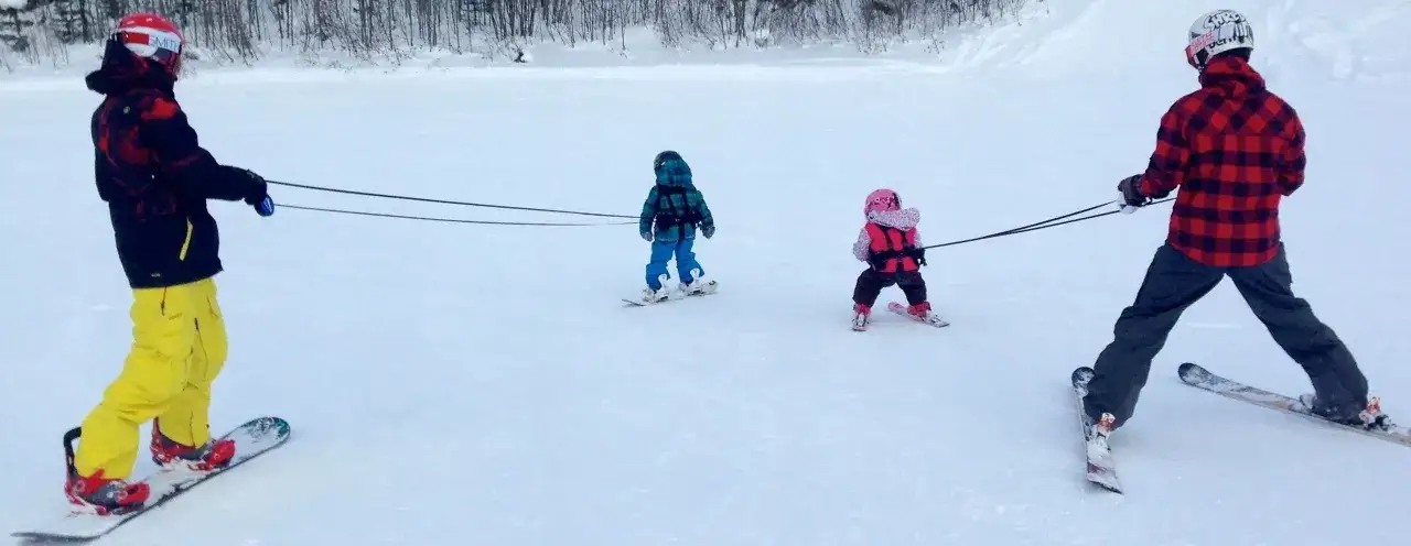 rodzic asekurujący dziecko na nartach