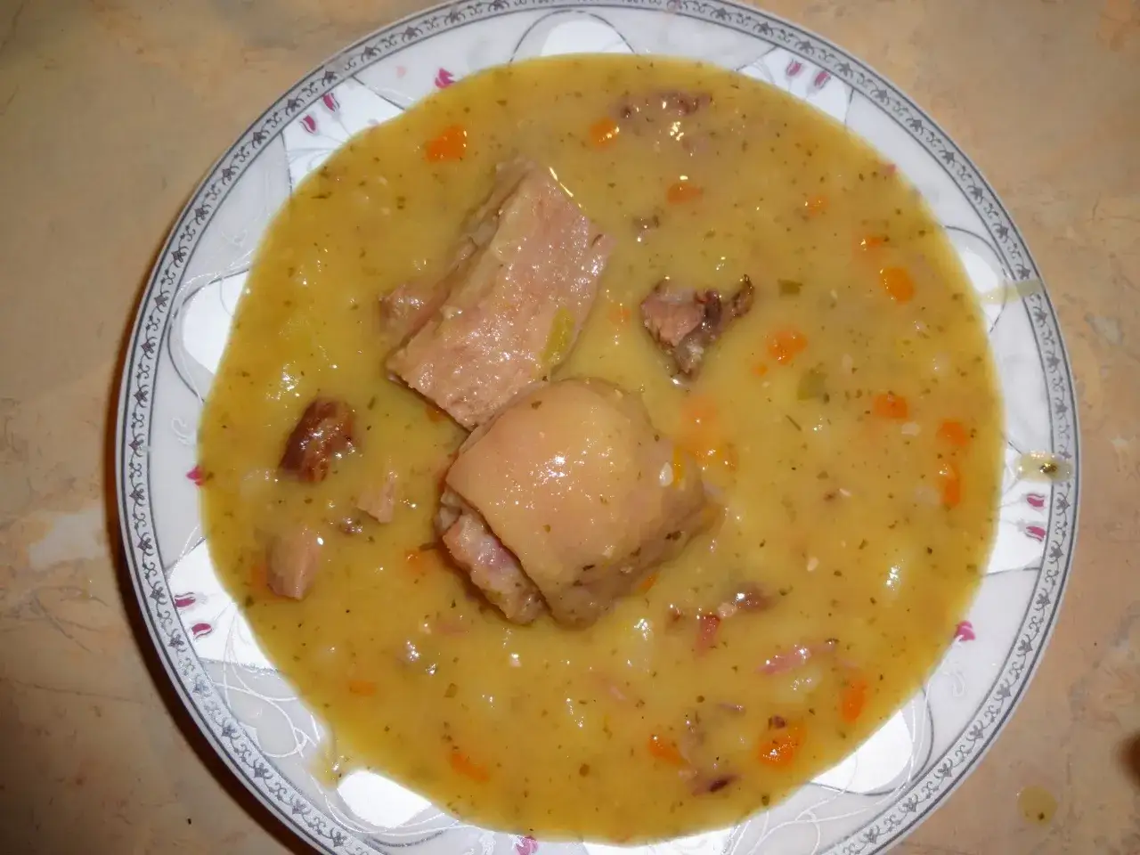 Gęsta, sycąca zupa grochowa, jaką można ugotować na golonce, z kawałkami mięsa i warzywami.