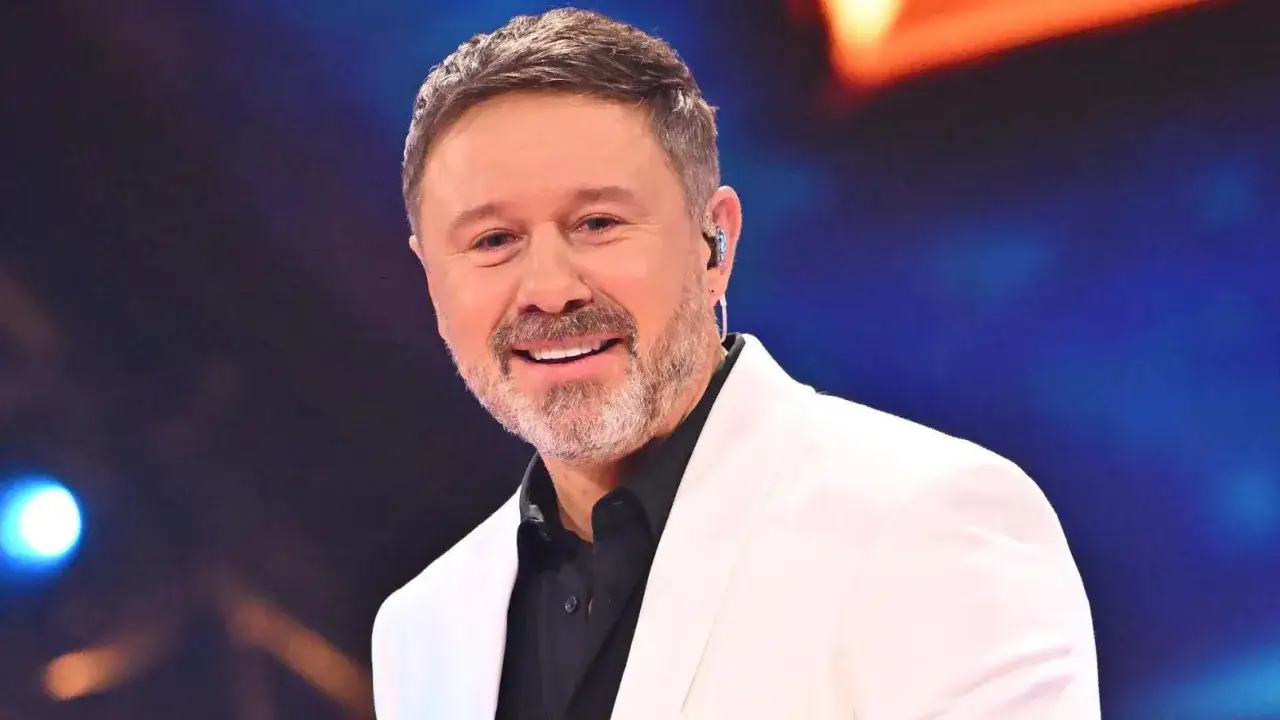 Uśmiechnięty Andrzej Piaseczny w białej marynarce. Czy Andrzej Piaseczny jest w związku? Jego uśmiech sugeruje, że tak!