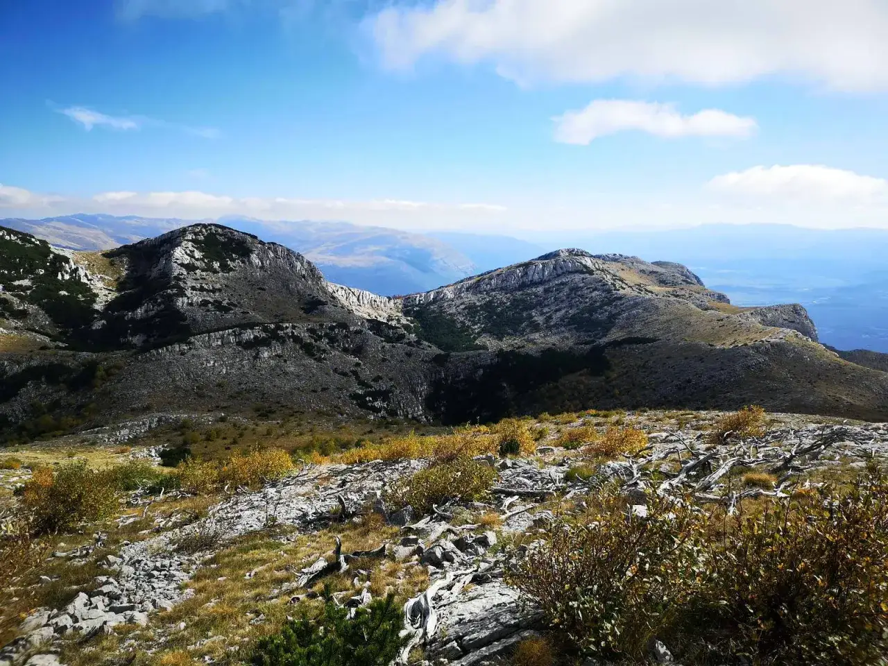 G&oacute;rzysty krajobraz Chorwacji z skalistymi szczytami i suchymi krzewami. W oddali widać kolejne pasma g&oacute;rskie. To widok z najwyższego szczytu w Chorwacji.