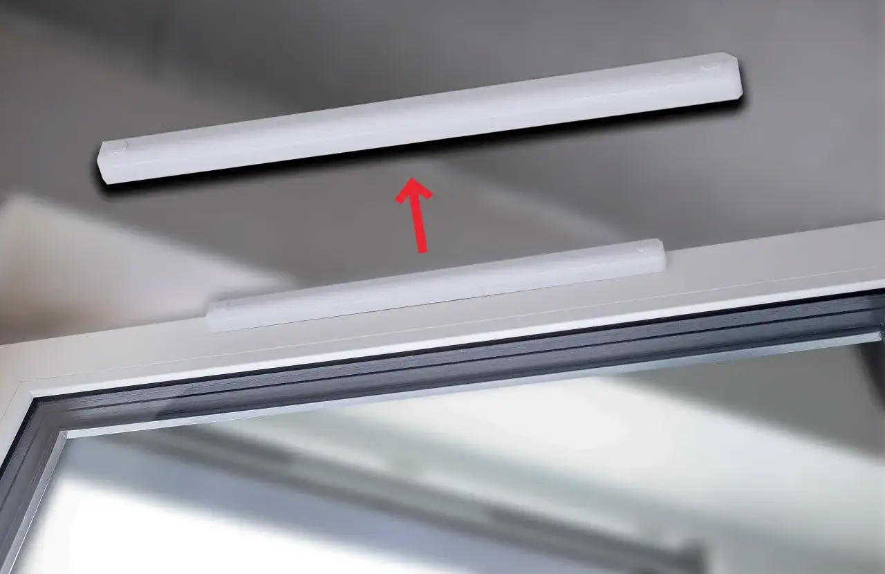 Białe listwy na oknie, jedna nad drugą, z czerwoną strzałką wskazującą ruch w górę. Ilustracja pokazuje, jak zamknąć wywietrzniki w oknach.
