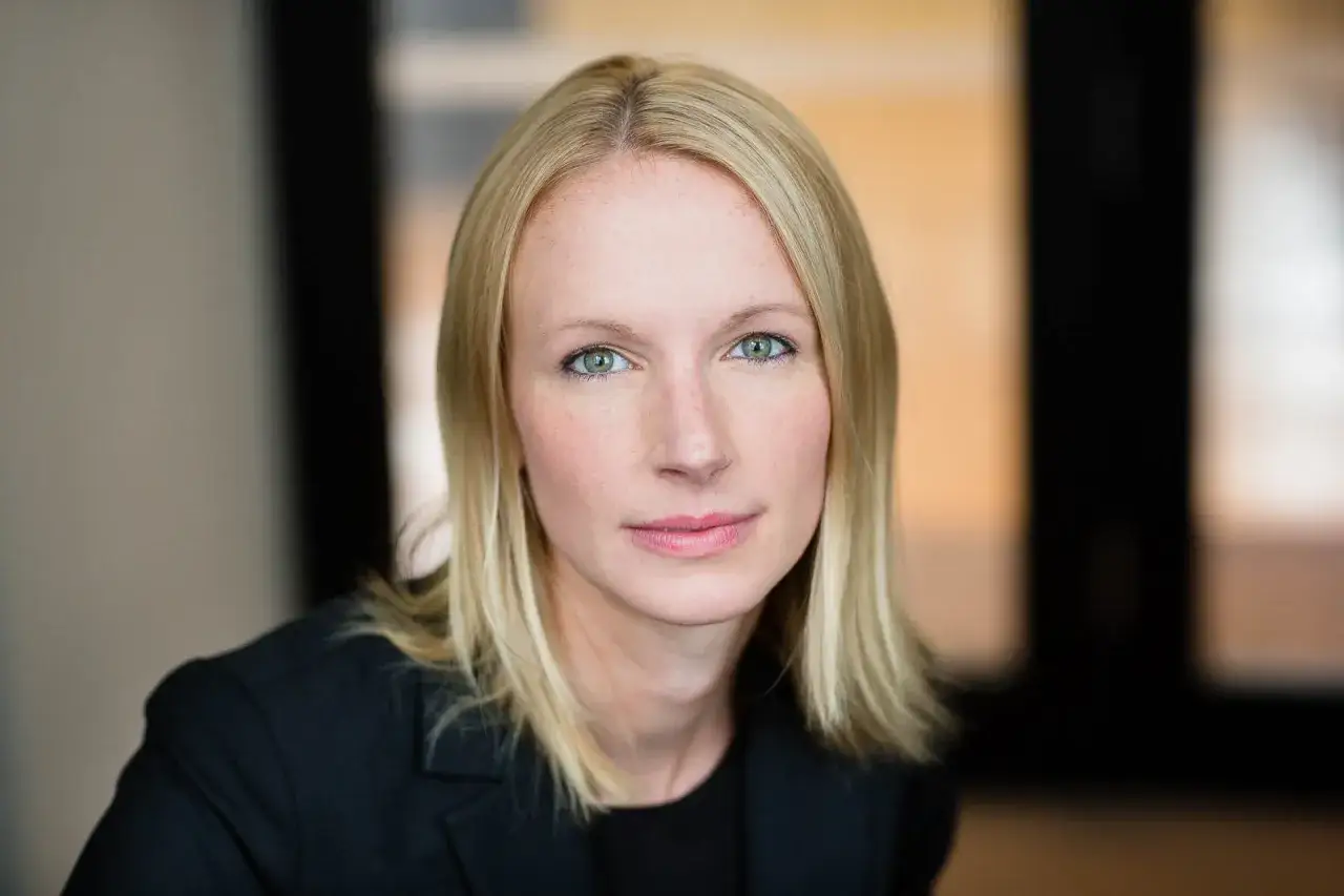 Portret kobiety z blond włosami i zielonymi oczami, w czarnej marynarce. To profesjonalna fotografia ludzi.