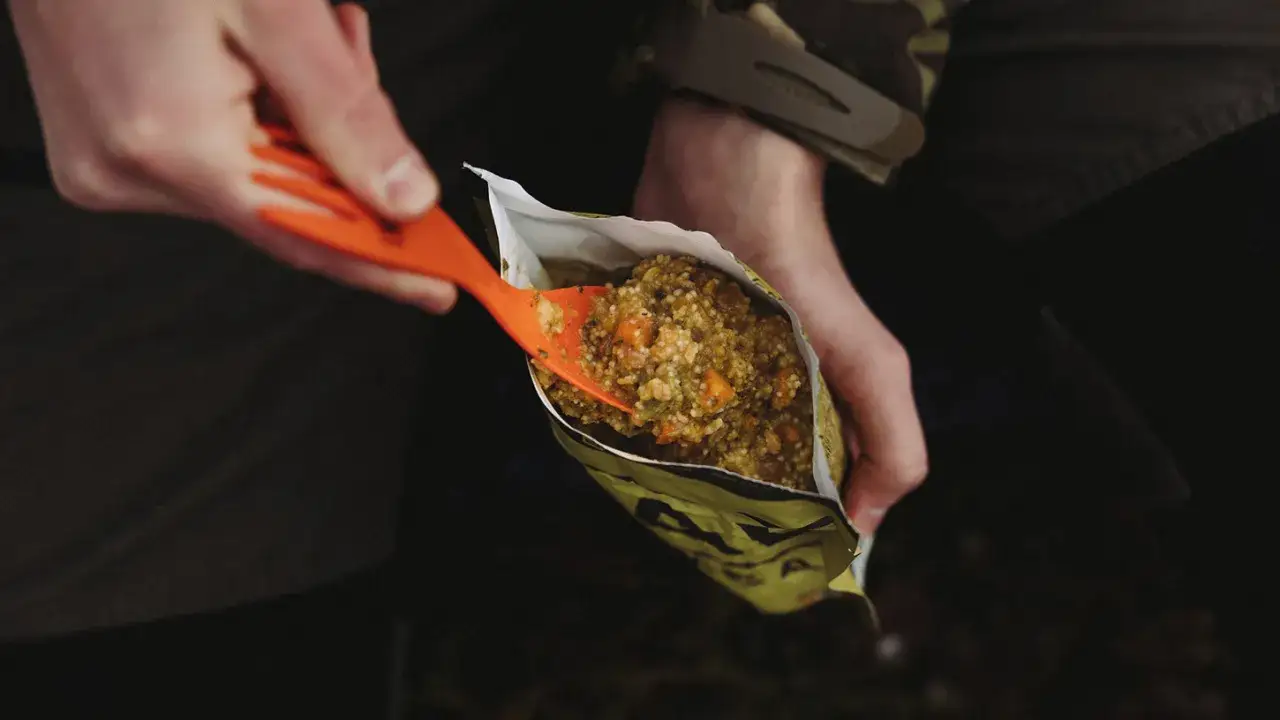 Nabieranie łyżką pożywnego jedzenia na biwak z paczki.