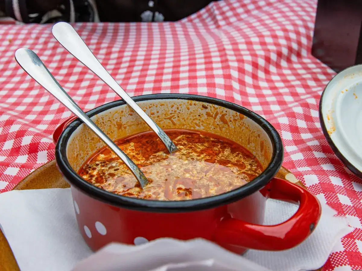 Gęsta, pikantna zupa w czerwonym garnuszku z białymi kropkami, z dwoma łyżkami. Idealna, by zniwelować ostrość zupy, gdy jest zbyt pikantna.