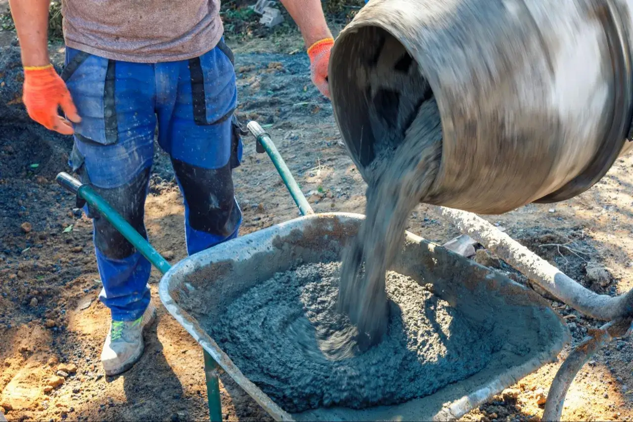 Robot budowlany wylewa świeży beton do taczki. To kluczowy etap, jak zrobić beton na budowie.