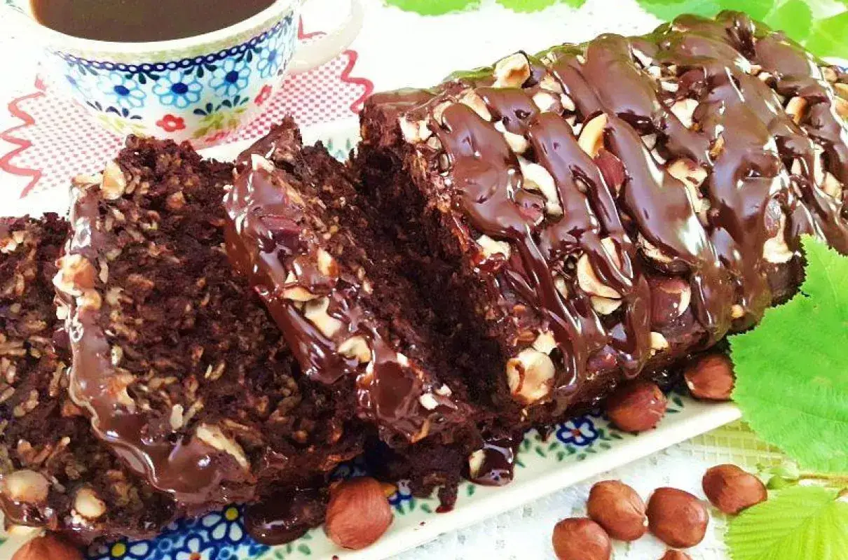 Pyszne ciasto z płatk&oacute;w owsianych bez mąki, polane czekoladą i orzechami. Idealne na zdrowe śniadanie lub deser.