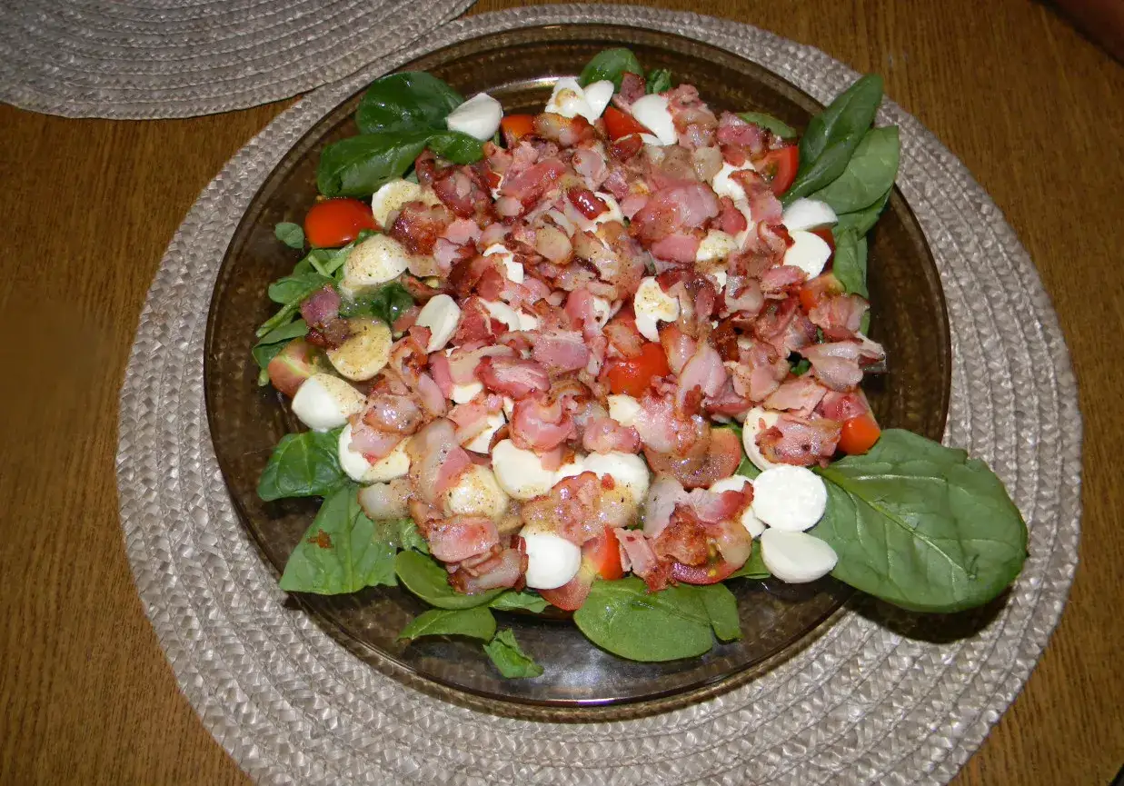 Pyszna sałatka ze szpinakiem, boczkiem i mozzarellą, polana sosem czosnkowym.