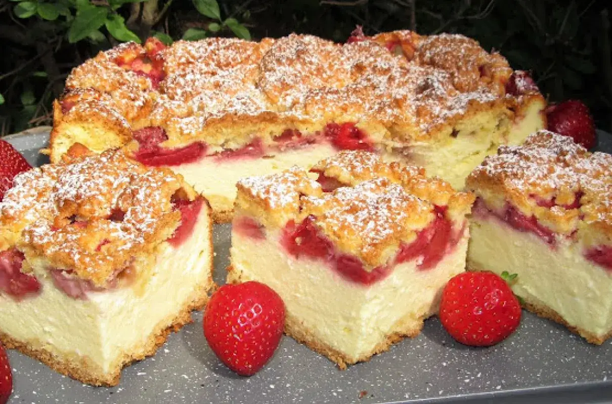 Pyszny sernikobrownie z truskawkami, posypany cukrem pudrem, prezentuje się apetycznie na szarym talerzu.