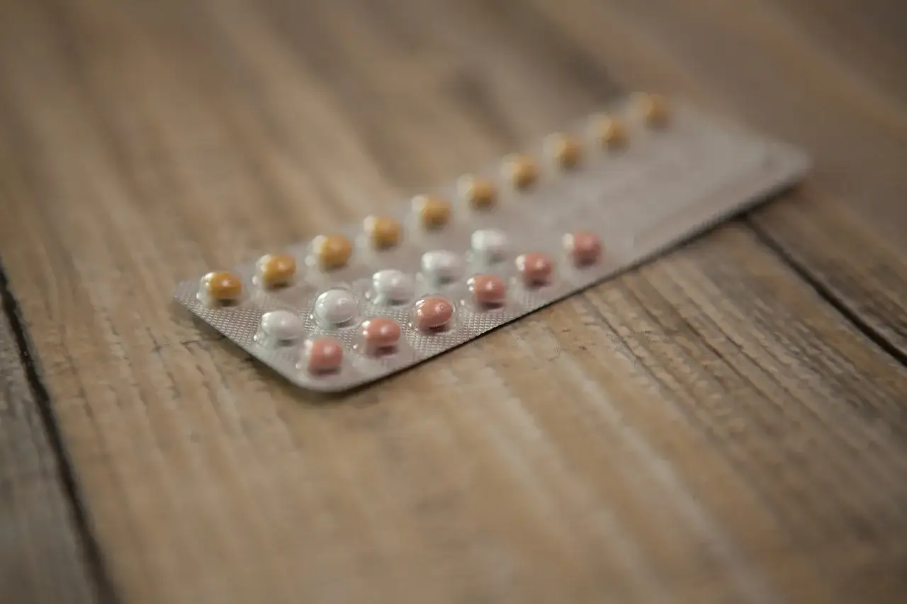 Opakowanie tabletek antykoncepcyjnych na drewnianym tle. Pytanie: czy podczas brania tabletek antykoncepcyjnych jest owulacja?