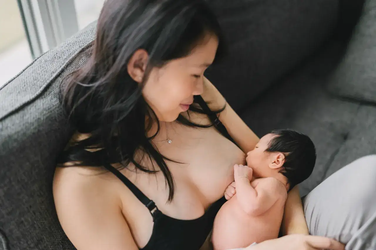 Mama karmi piersią swoje maleństwo. Czuły moment, gdy dziecko pije mleko z piersi.