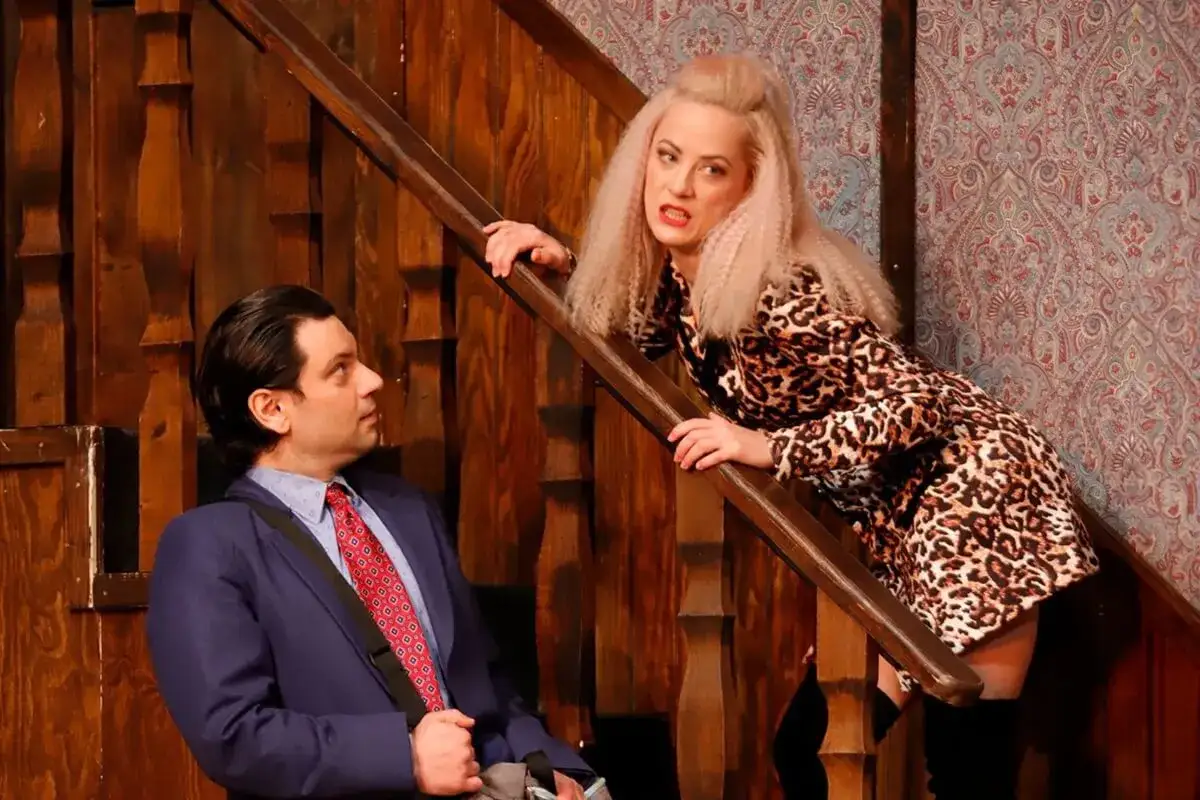 Na schodach Teatru Osterwy mężczyzna w garniturze rozmawia z kobietą w panterce.