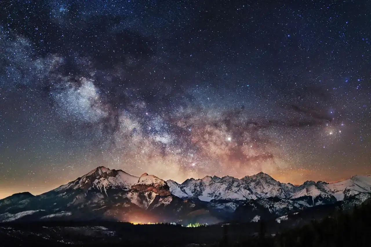 aparat fotograficzny z szerokokątnym obiektywem na statywie w nocy, widoczna Droga Mleczna