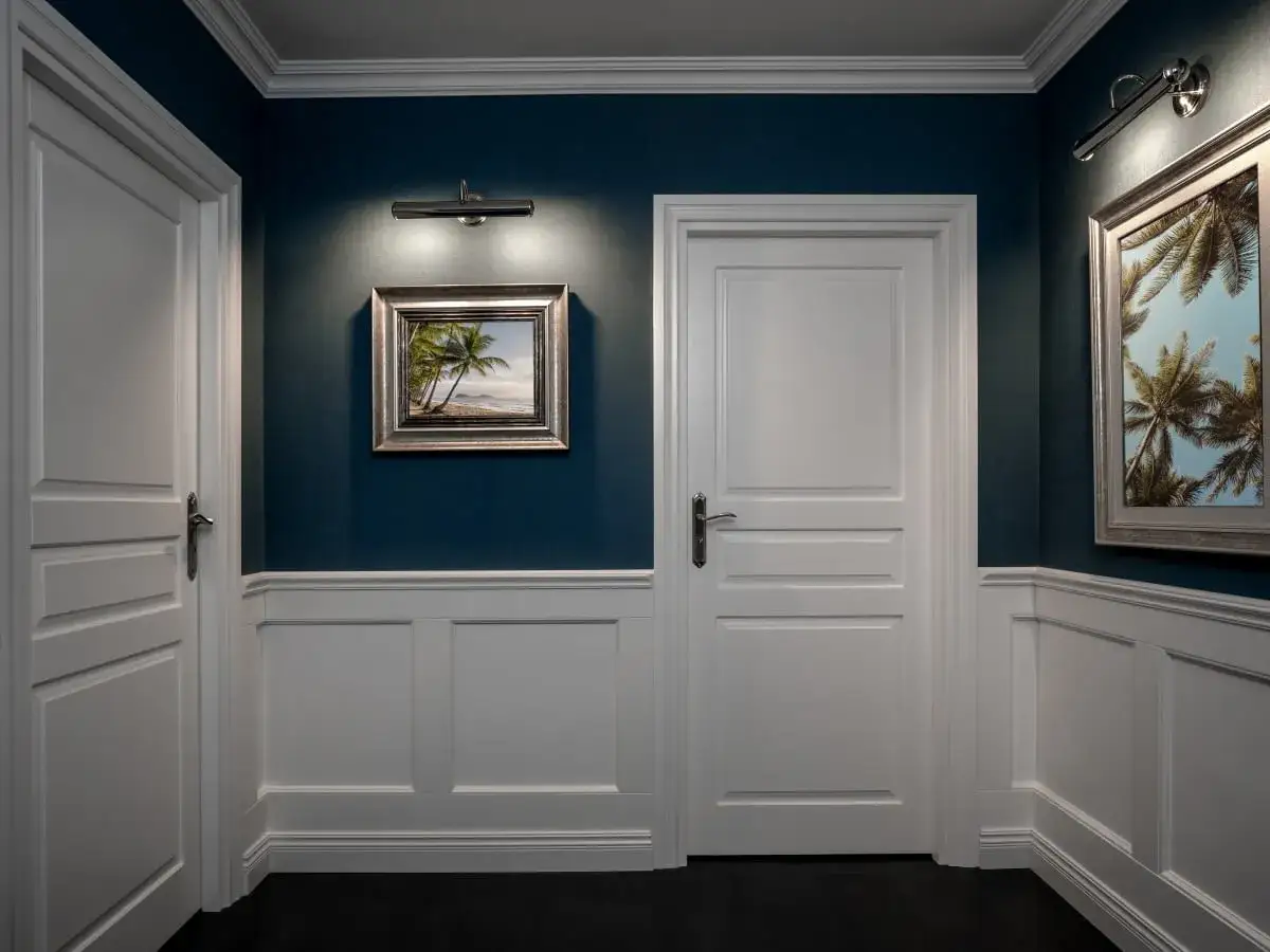 Elegancka boazeria angielska inspiracje: ciemnoniebieskie ściany, białe drzwi i panele, obrazy z palmami.