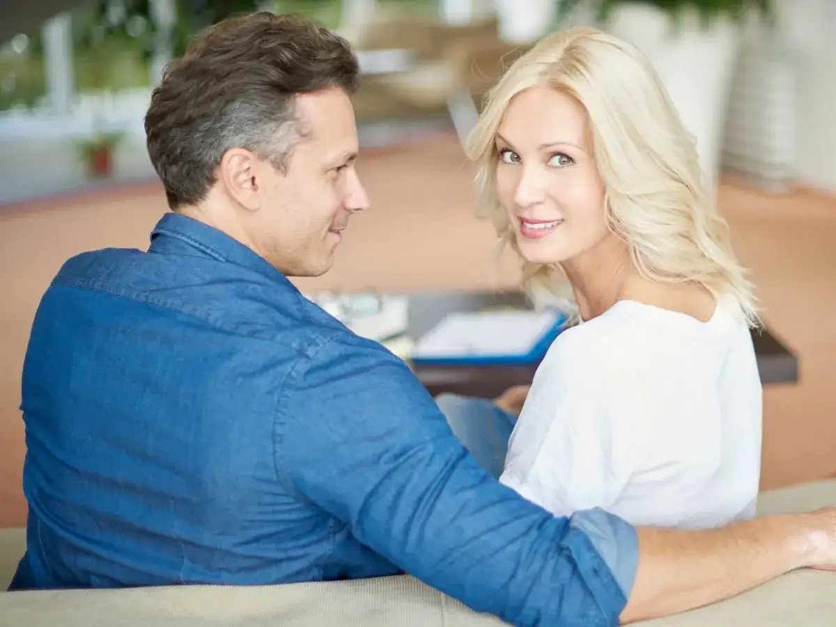 Para udana, w trakcie randek z kobietami, mężczyzna w dżinsowej koszuli patrzy na uśmiechniętą blondynkę.