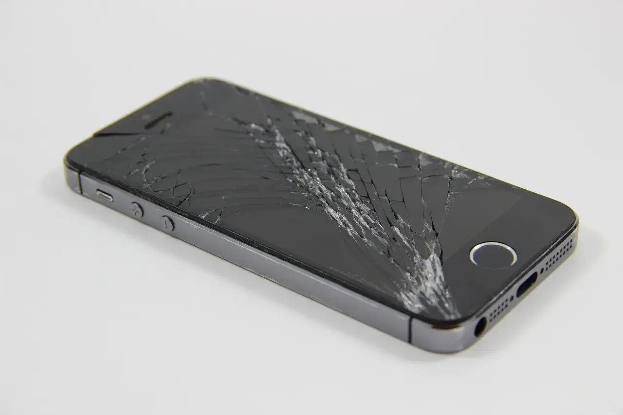 Telefon z pękniętym szkłem hartowanym, pajęczynka pęknięć na ekranie.