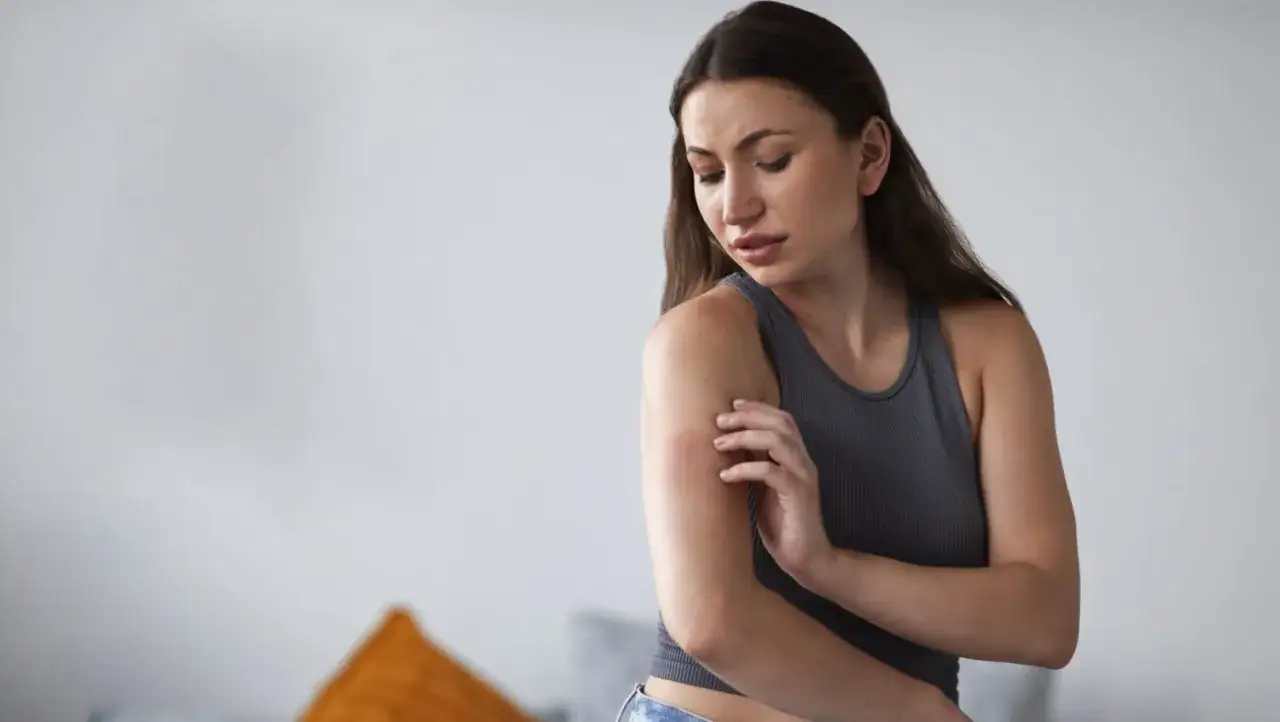 Kobieta drapie się po ramieniu, odczuwając dyskomfort. Czy to mogą być bóle somatyczne?