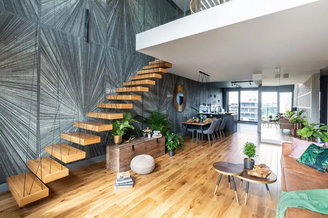 Nowoczesna antresola z drewnianymi stopniami wiszącymi na linach, nad jadalnią i kuchnią.