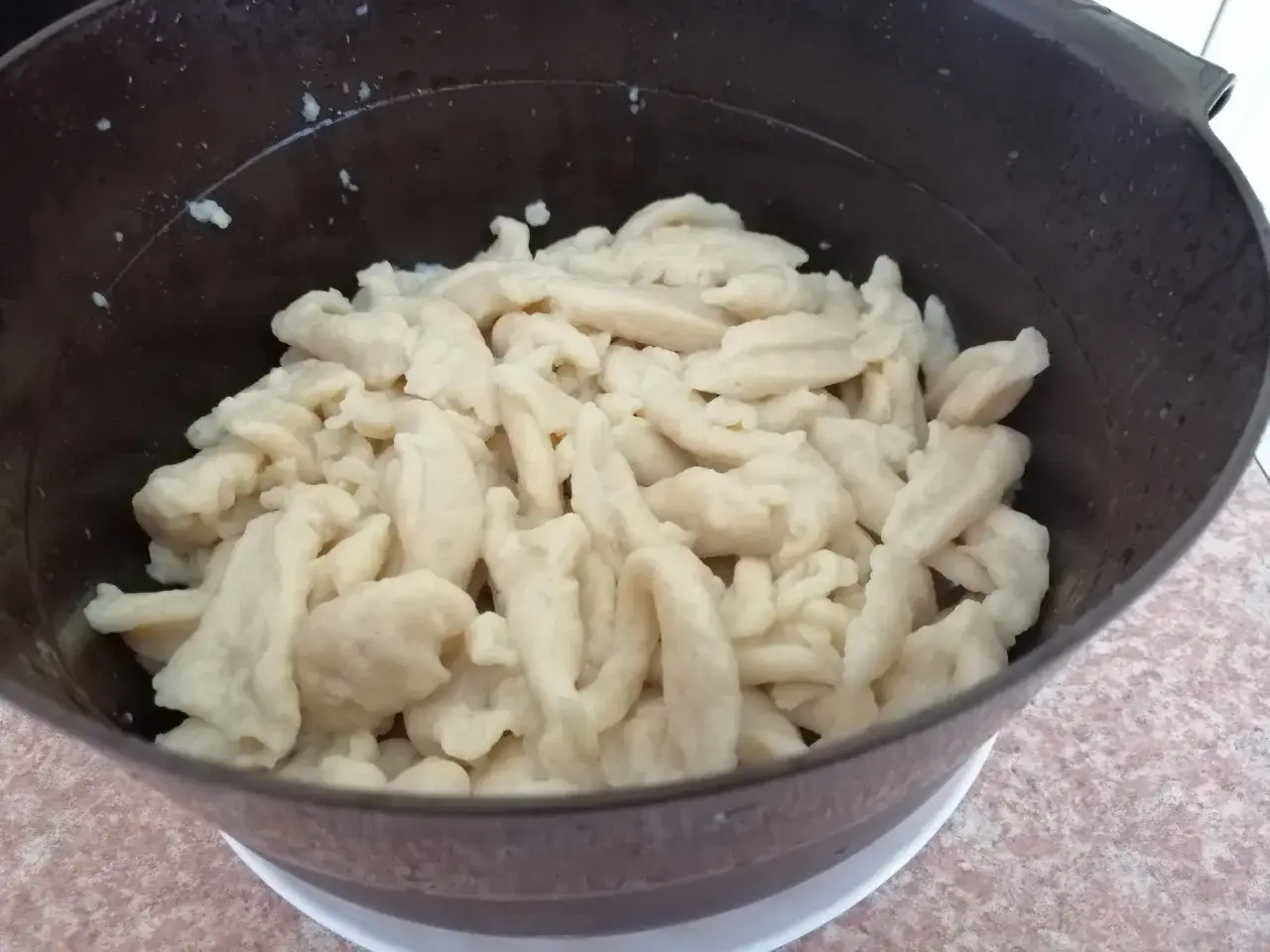 Osoba kładąca kluski łyżką do wrzątku