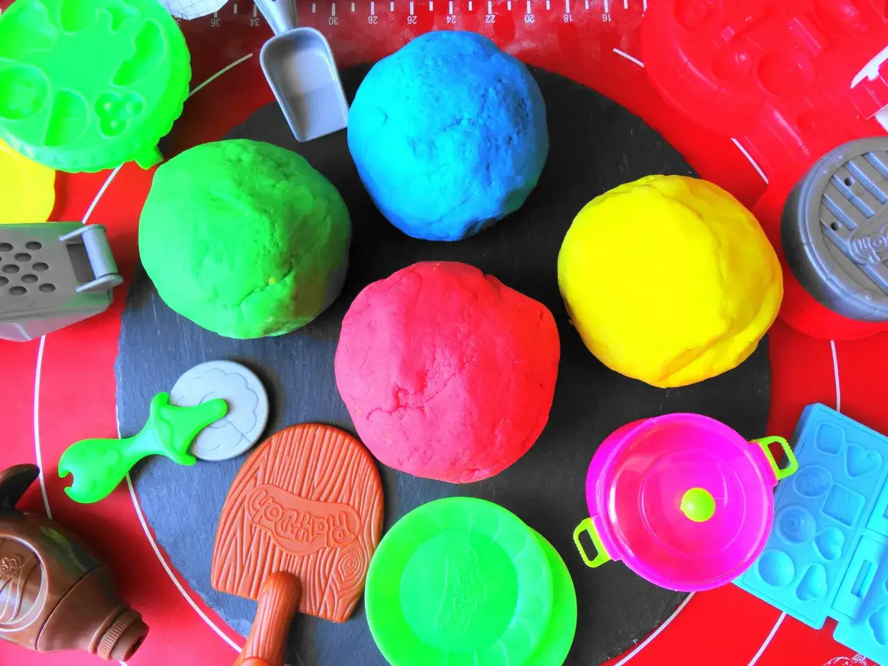 Kolorowe kulki ciastoliny i akcesoria do zabawy. Zobacz, jak zrobić ciastolinę w domu!