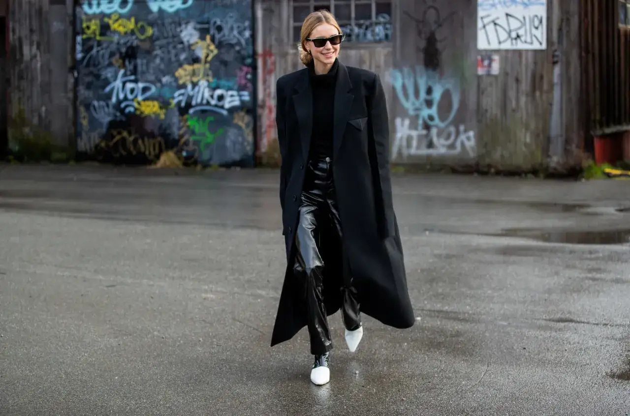 Elegancka stylizacja: czarny płaszcz, golf i błyszczące spodnie. Idealna inspiracja, co założyć do czarnych szerokich spodni.