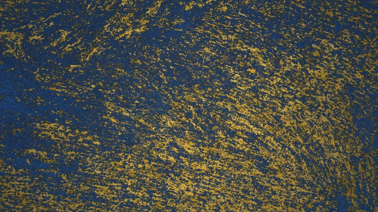 Niebieska ściana z efektem brokatu. Złote drobinki tworzą nieregularne wzory, jak nałożyć brokat na ścianę, by uzyskać taki efekt.