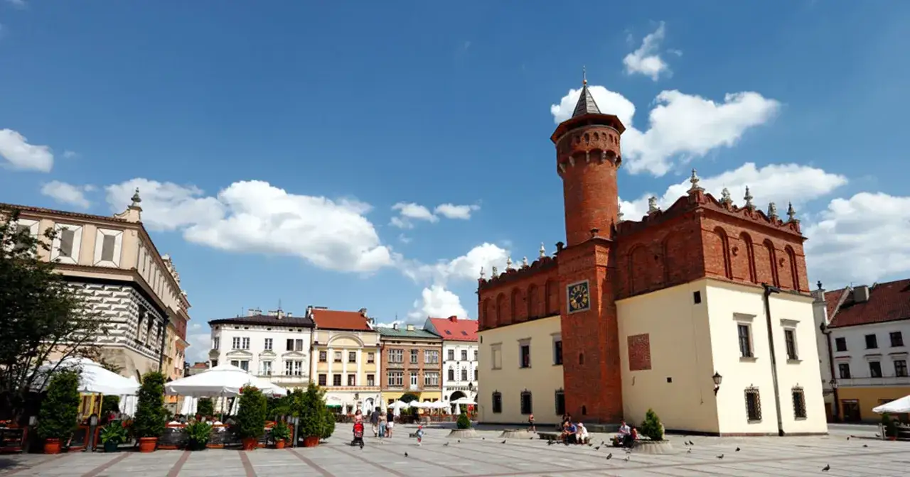 Rynek w Tarnowie, polskim biegunie ciepła, tętni życiem. W tle widać ratusz i kolorowe kamienice.