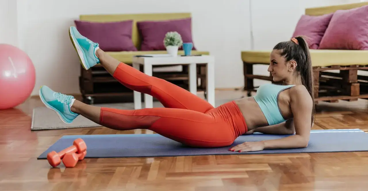 Kobieta wykonuje ćwiczenia na schudnięcie z brzucha, leżąc na macie.