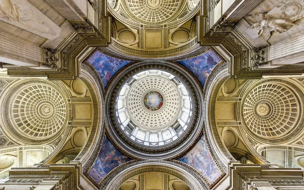 Wnętrze Panteonu w Paryżu, z widokiem na kopułę i zdobione sufity. Monumentalna architektura zachwyca detalami.