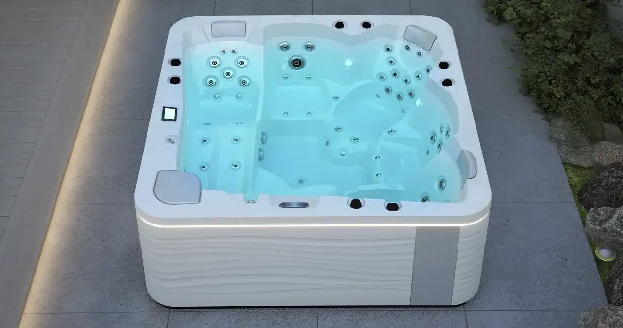 Nowoczesna wanna wanna spa ogrodowa z błękitną wodą i dyszami, otoczona kamieniami i zielenią.