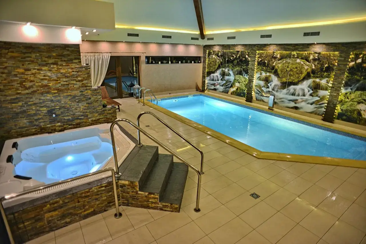 Relaks w hotelu z basenem na Podlasiu: basen, jacuzzi i wodospady na ścianie.