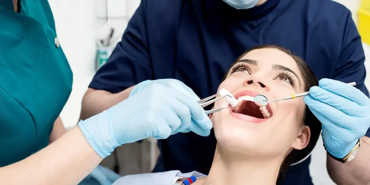Pacjent po wizycie u dentysty, dłoń na policzku, zmartwiona twarz, dentysta udziela wskaz&oacute;wek