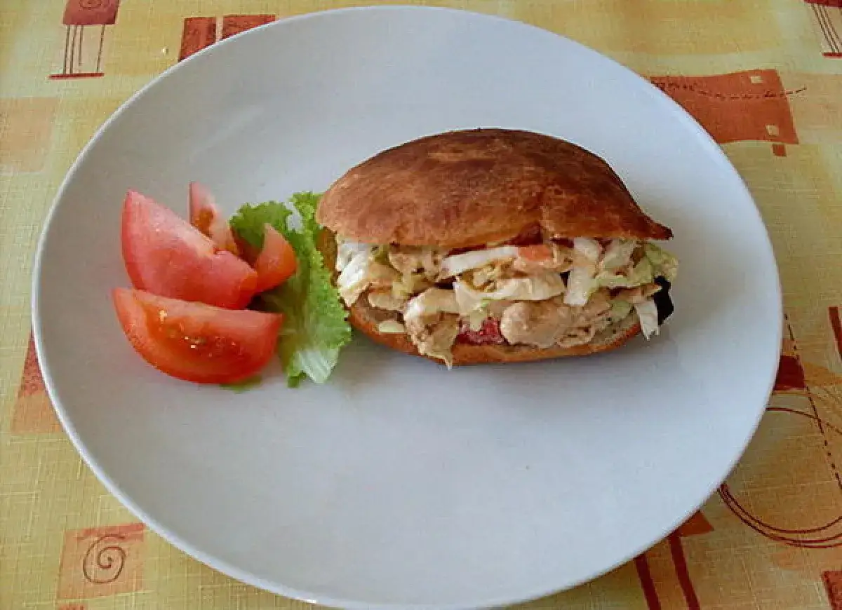 Pyszny kebab w picie z kurczakiem, warzywami i sosem, podany z pomidorami i sałatą na białym talerzu.