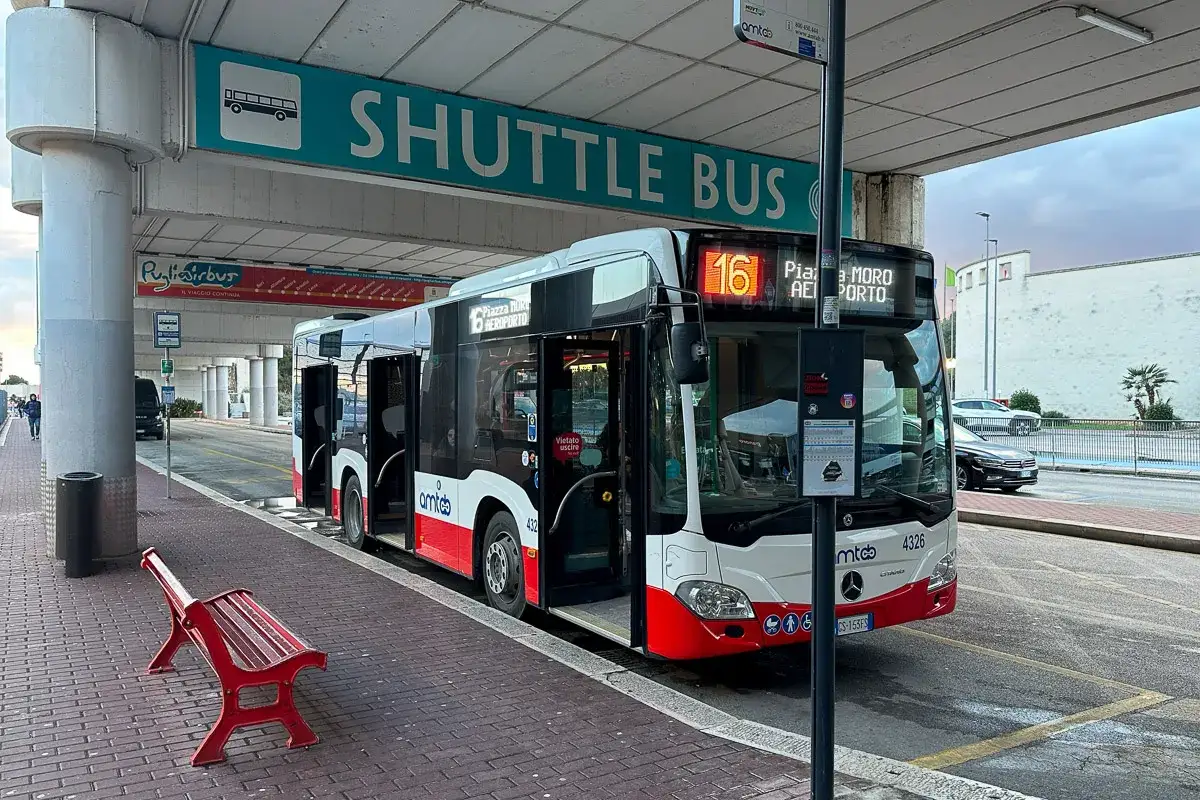 Autobus wahadłowy z lotniska do centrum miasta. Czerwona ławka czeka na pasażer&oacute;w.