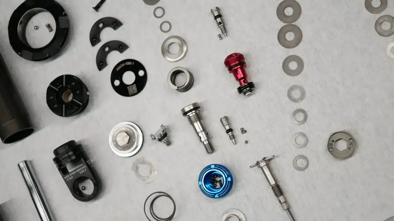 Rozłożony amortyzator rowerowy. Widać sprężyny, tłoczysko i podkładki. Amortyzator w rowerze nie ugina się, gdy jest rozłożony.