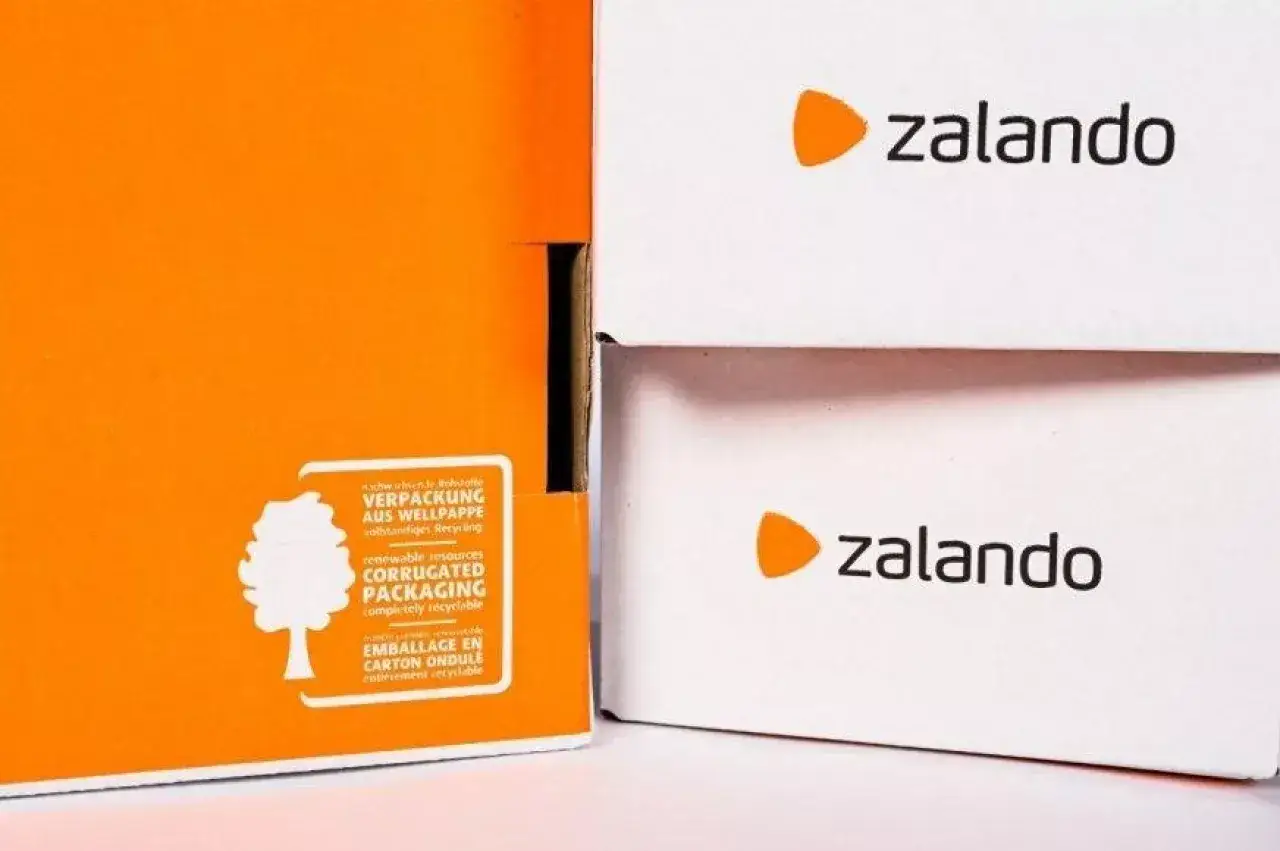 Dwie białe paczki z logo Zalando i jedna pomarańczowa z informacją o recyklingu. Czy Zalando jest legit? Tak, to popularny sklep.