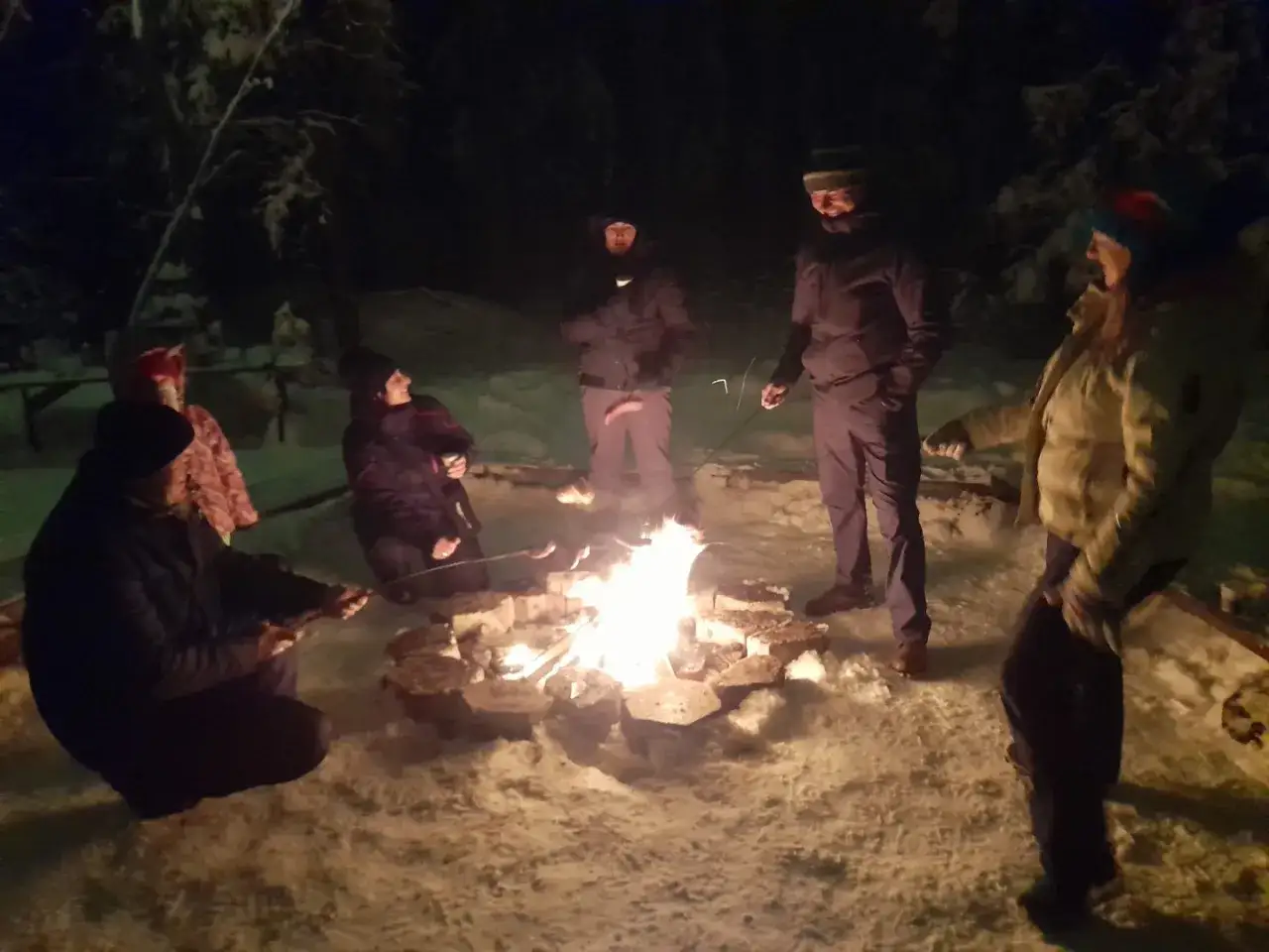 Grupa ludzi piecze kiełbaski nad ogniskiem podczas kuligu w Bukowinie Tatrzańskiej.