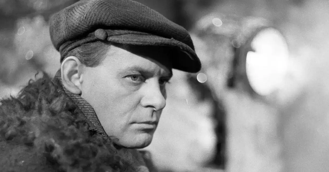 Tadeusz Łomnicki w czapce i futrzanym kołnierzu, postać z film&oacute;w, seriali i program&oacute;w.